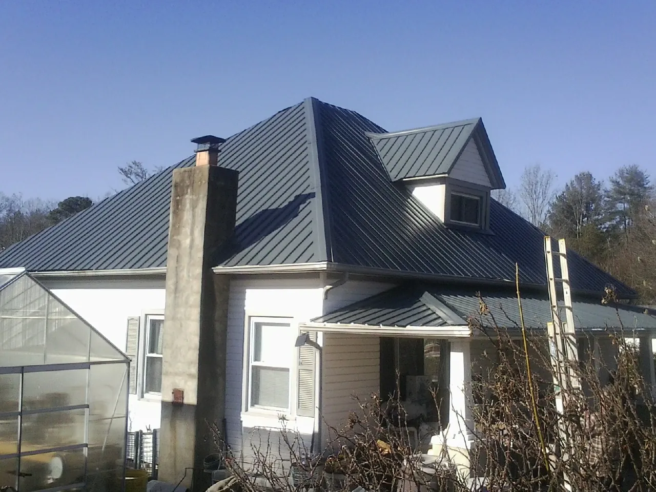Dark blue standing seam metal roof on a white farmhouse with dormer — Slate & Tile Roof Repair by Roofing Brothers in Society Hill