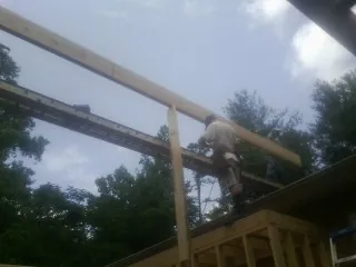 Carpenter setting a ridge beam over a new addition frame — Ice Dam Removal by Roofing Brothers in Society Hill