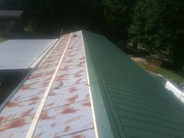 Old rusted panels beside newly installed green metal roofing — Wind Damage Roof Repair by Roofing Brothers in Society Hill