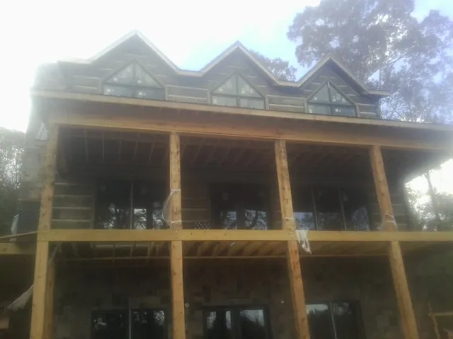 Dormers and porch framing on a large log home under construction — Roof Coating work by our crew in Society Hill