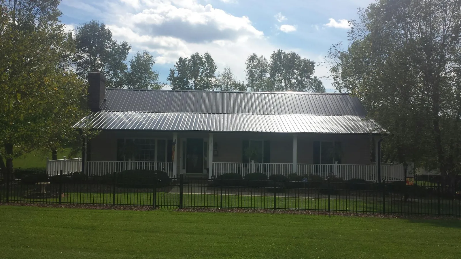 Gray metal roof on a brick ranch with a full width front porch — Gutter Guard Installation work by our crew in Society Hill