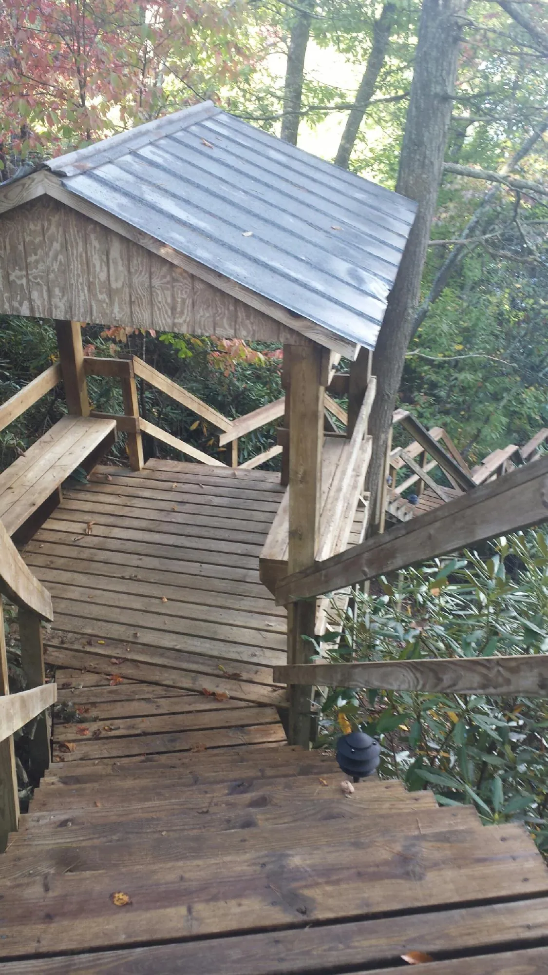 Metal roofed shelter over wooden steps on a wooded walkway — Skylight Repair & Installation work by our crew in Society Hill