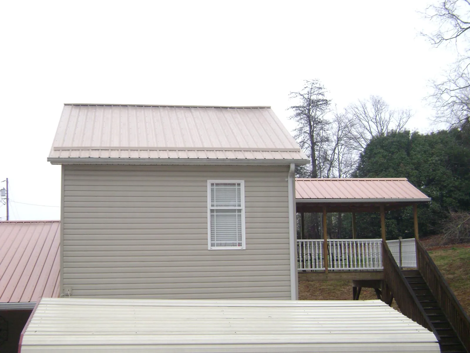 Tan metal roofs on a two story addition and attached porch, from a Roof Replacement job in Society Hill