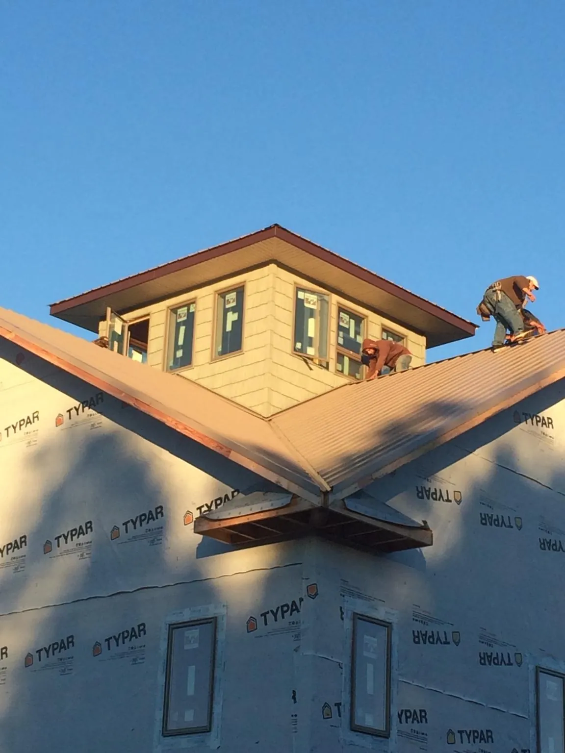 Roofers working around a rooftop cupola on a new metal roof at sunset — Roof Waterproofing in Society Hill by Roofing Brothers